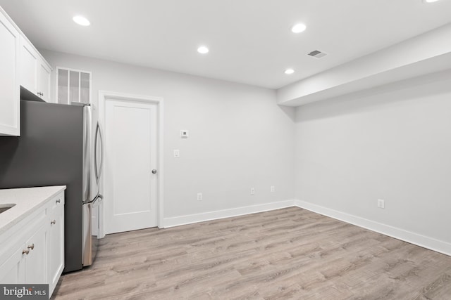 kitchen featuring white cabinets, freestanding refrigerator, light wood-style flooring, and visible vents