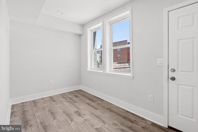 empty room featuring a healthy amount of sunlight, baseboards, and wood finished floors