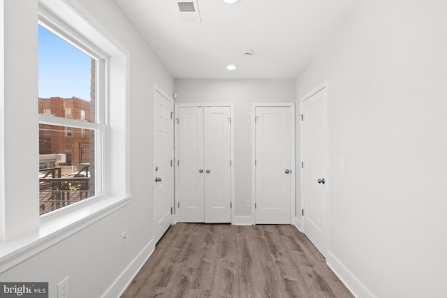 corridor featuring plenty of natural light, recessed lighting, baseboards, and wood finished floors