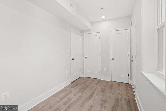 interior space featuring multiple closets, baseboards, light wood-type flooring, and visible vents