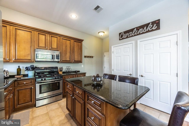 kitchen featuring a kitchen breakfast bar, a center island, stainless steel appliances, light tile patterned floors, and visible vents