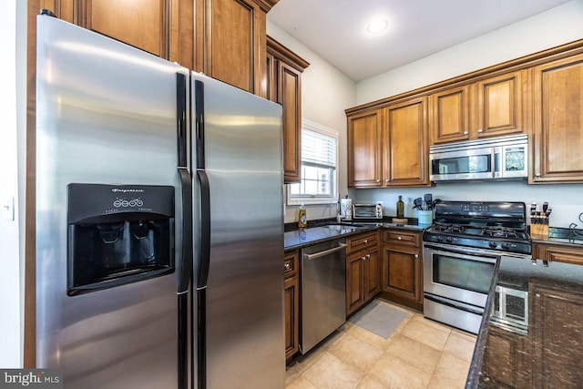 kitchen with dark stone counters, appliances with stainless steel finishes, recessed lighting, and brown cabinets