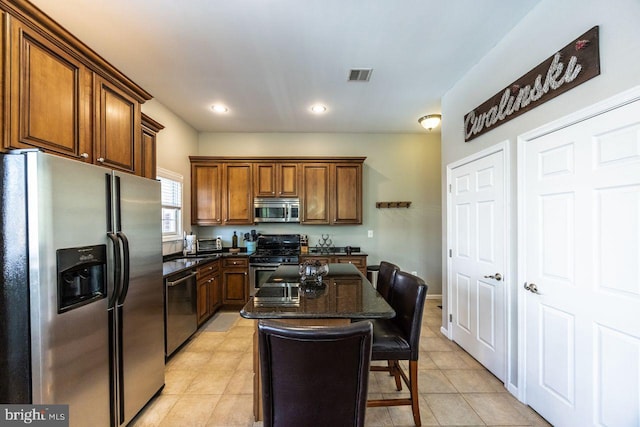 kitchen featuring visible vents, a center island, a breakfast bar, stainless steel appliances, and light tile patterned flooring