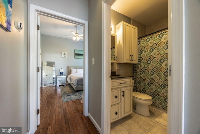 full bath with vanity, hardwood / wood-style floors, toilet, a shower with shower curtain, and ceiling fan