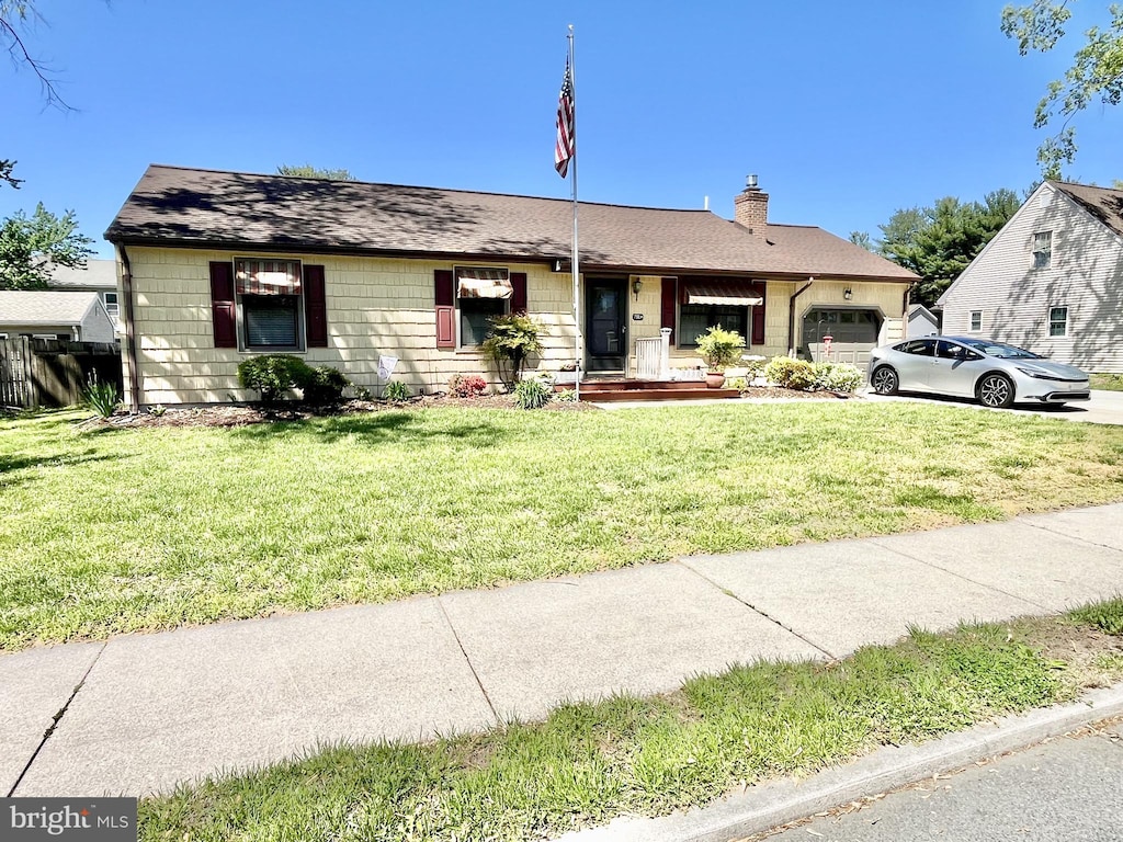 view of front of home featuring a garage, a front lawn, a chimney, and concrete driveway