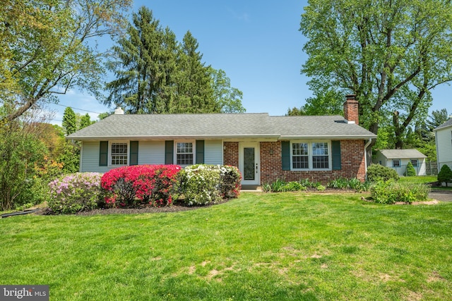 ranch-style home with brick siding, a chimney, and a front lawn