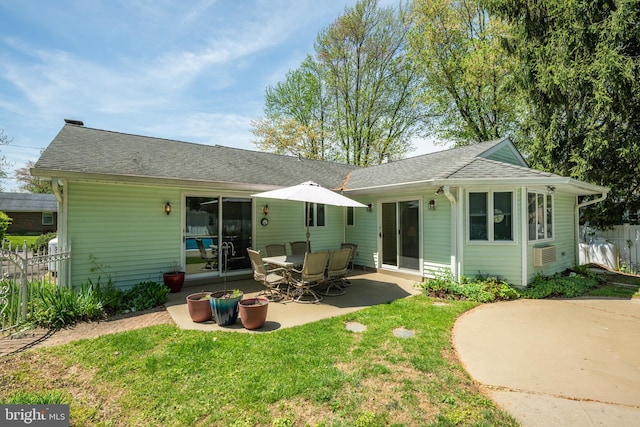 rear view of property featuring fence, a patio, a shingled roof, and a lawn