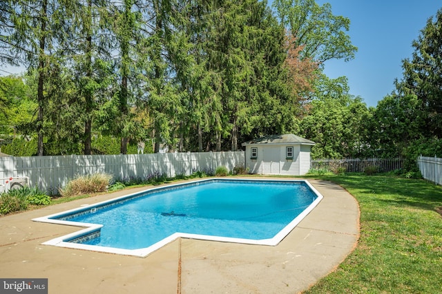 view of swimming pool with a fenced backyard, a fenced in pool, an outbuilding, a patio area, and a yard