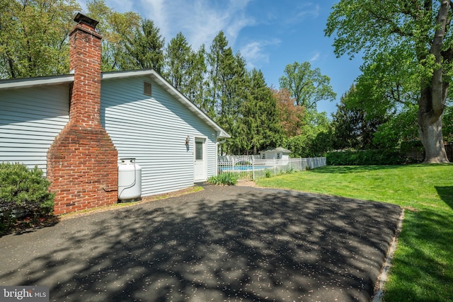 view of property exterior with fence, a yard, and a chimney