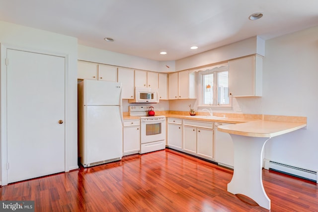 kitchen featuring a sink, baseboard heating, white appliances, light countertops, and wood finished floors