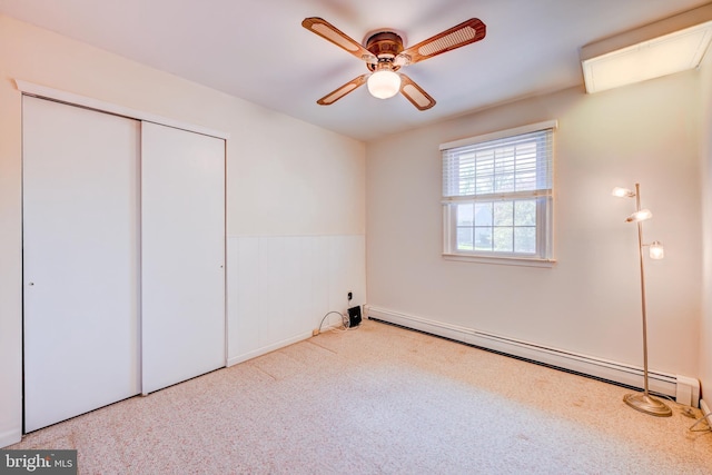 unfurnished bedroom with a closet, a ceiling fan, a baseboard heating unit, and carpet flooring