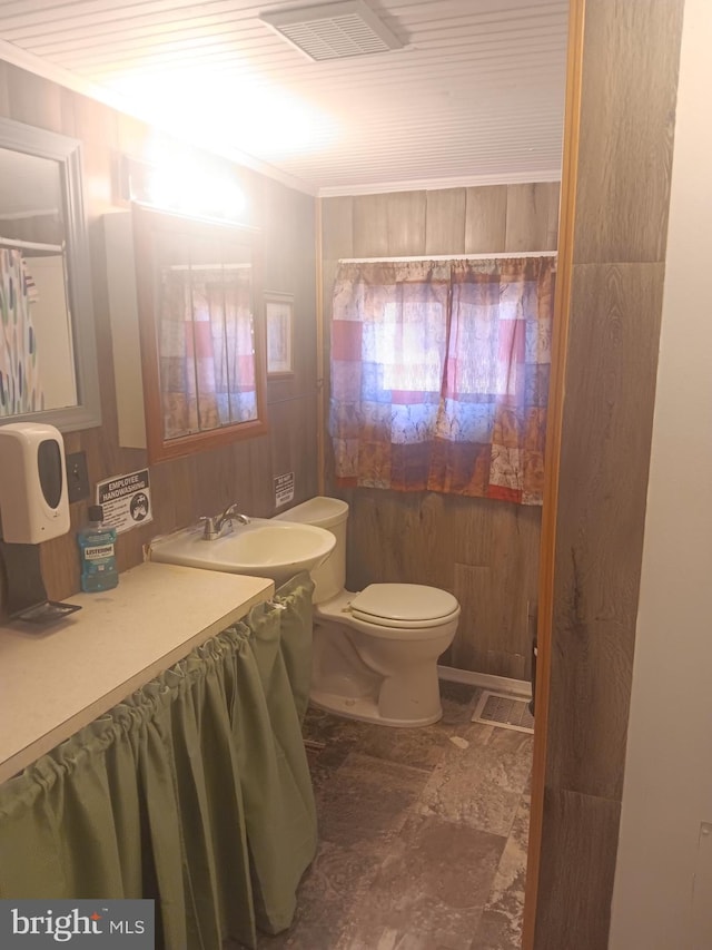 bathroom with visible vents, wood walls, toilet, a sink, and stone finish flooring