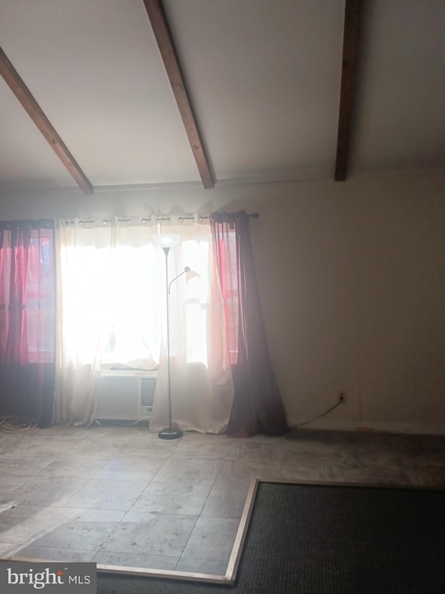 empty room featuring vaulted ceiling with beams
