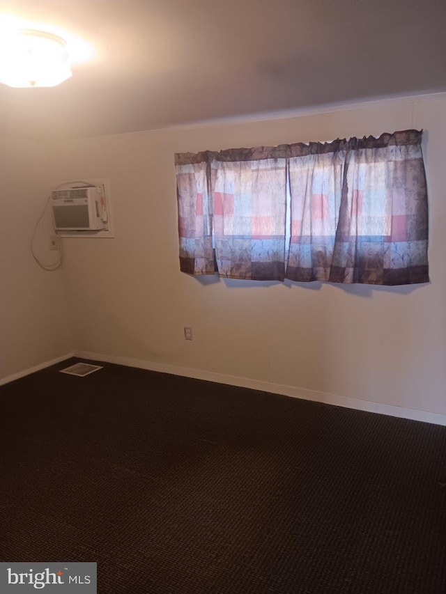 carpeted spare room featuring baseboards and an AC wall unit