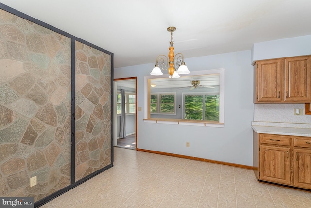 unfurnished dining area featuring baseboards and ceiling fan with notable chandelier