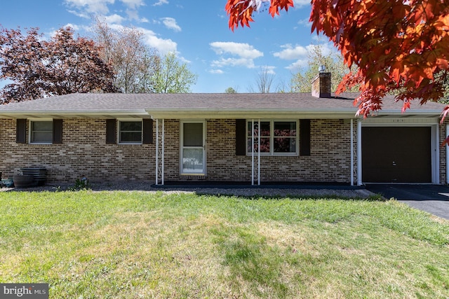 ranch-style house featuring a chimney, a garage, brick siding, aphalt driveway, and a front lawn