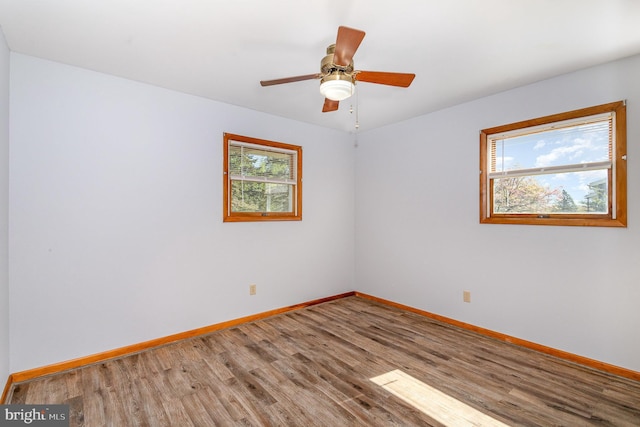 spare room with baseboards, ceiling fan, and wood finished floors