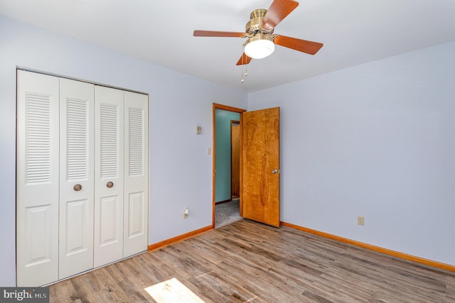 unfurnished bedroom with baseboards, a ceiling fan, wood finished floors, and a closet