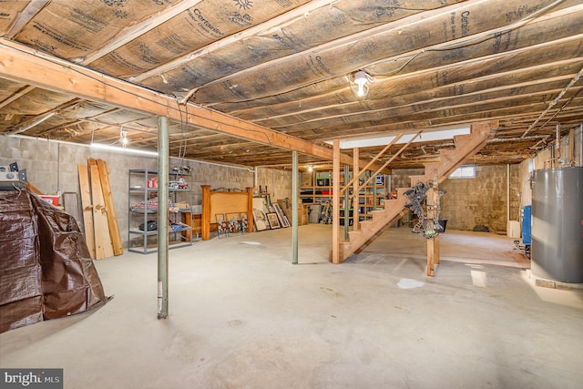 unfinished basement featuring water heater and stairway