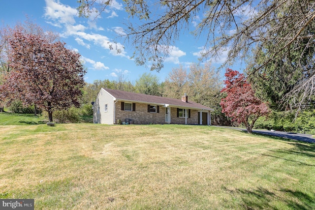 single story home with brick siding, a front yard, and a chimney