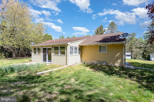 rear view of property with a lawn, roof with shingles, and a sunroom