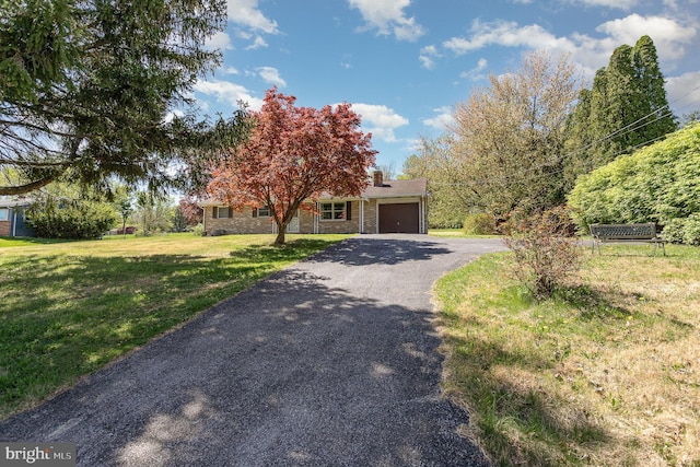 view of property hidden behind natural elements with a garage, a chimney, driveway, and a front lawn