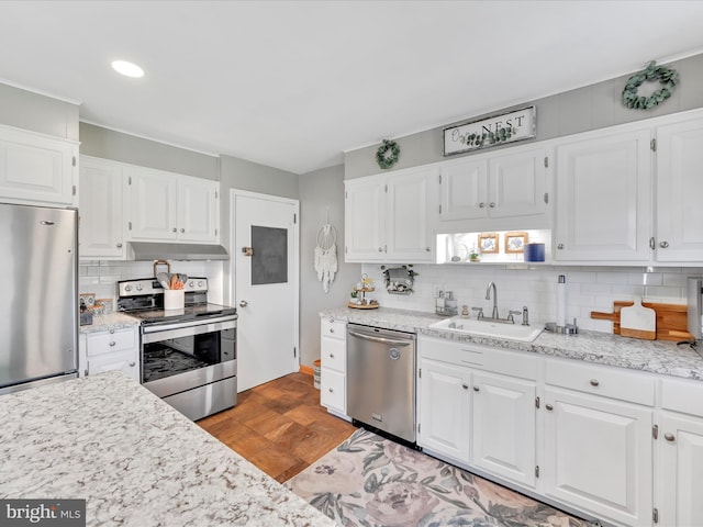 kitchen featuring decorative backsplash, under cabinet range hood, white cabinets, a sink, and stainless steel appliances