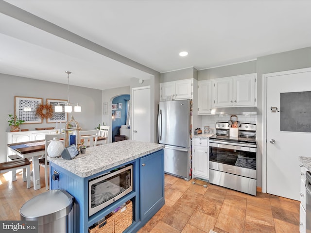 kitchen featuring blue cabinetry, stainless steel appliances, white cabinetry, decorative backsplash, and under cabinet range hood