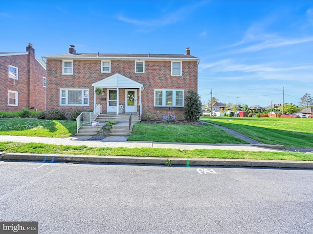 view of front of home with a chimney, a front lawn, and brick siding