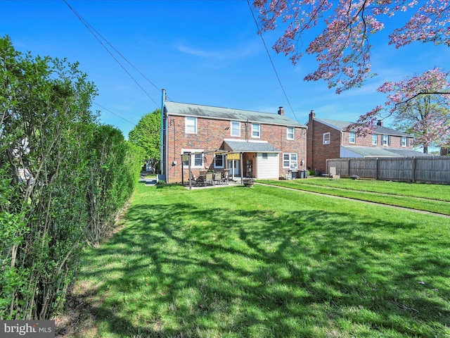 rear view of house featuring brick siding, a patio area, fence, and a yard