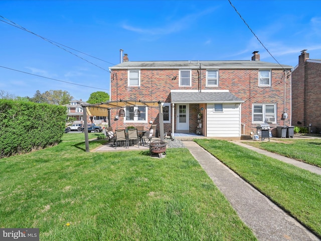 back of property with a yard, brick siding, a chimney, and a patio area