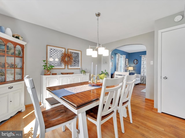 dining area with arched walkways and light wood-style flooring