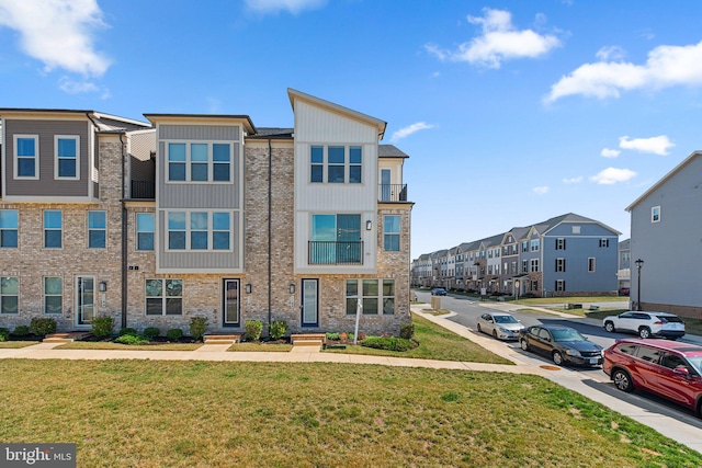 townhome / multi-family property featuring a front lawn, uncovered parking, board and batten siding, and a residential view