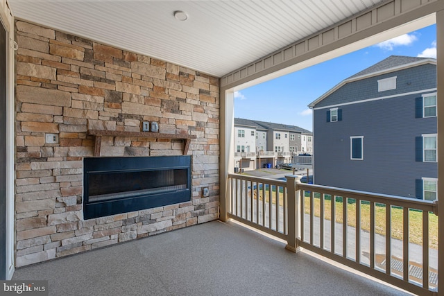 balcony with an outdoor stone fireplace and a residential view