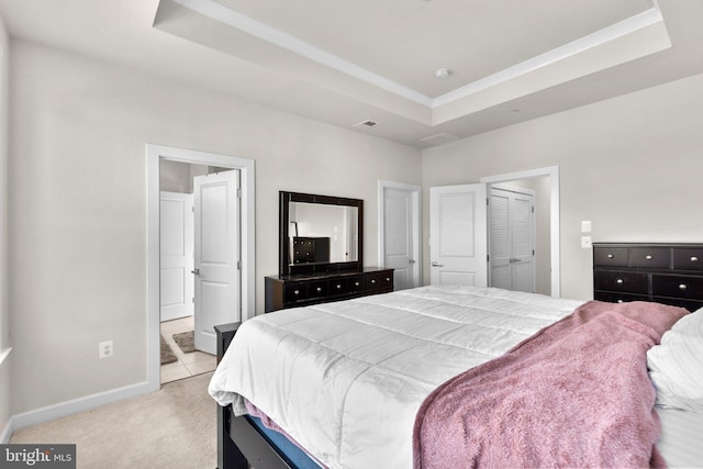 bedroom with baseboards, light carpet, ensuite bathroom, and a raised ceiling