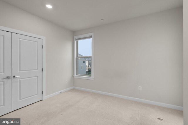 unfurnished bedroom with baseboards, recessed lighting, a closet, and light carpet