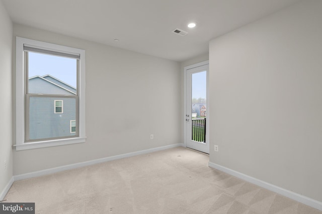 unfurnished room featuring visible vents, baseboards, and plenty of natural light