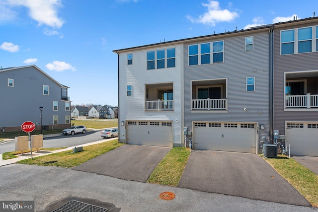 exterior space with a garage, driveway, a residential view, and central AC unit