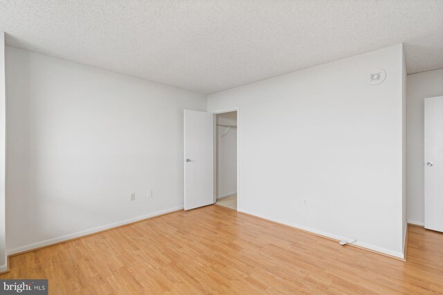 unfurnished bedroom with light wood-style floors, baseboards, and a textured ceiling
