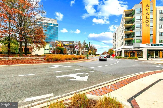 view of asphalt road with curbs, traffic signs, street lighting, and sidewalks