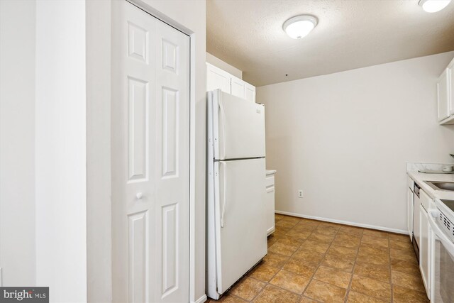 3203 Forest Run Dr, District Heights, MD 20747 - kitchen with freestanding refrigerator, a textured ceiling, light countertops, white cabinets, and baseboards