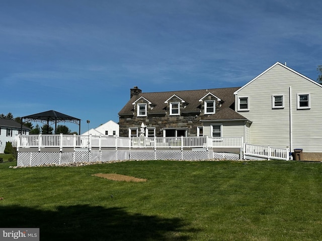 rear view of property featuring a gazebo, a chimney, a yard, and a deck