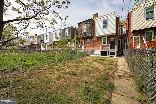 back of property with a fenced backyard, a residential view, and brick siding