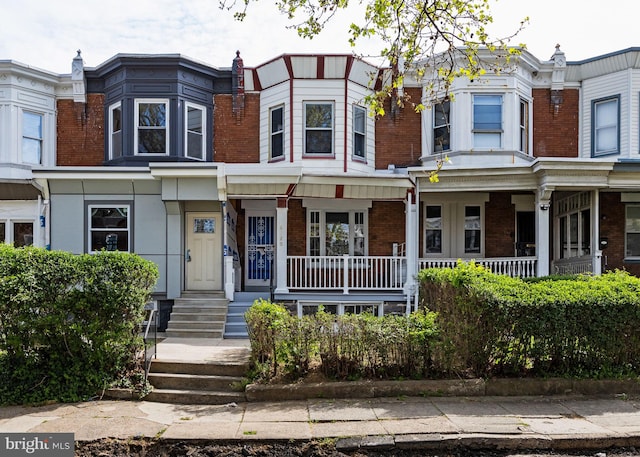 townhome / multi-family property featuring brick siding and covered porch