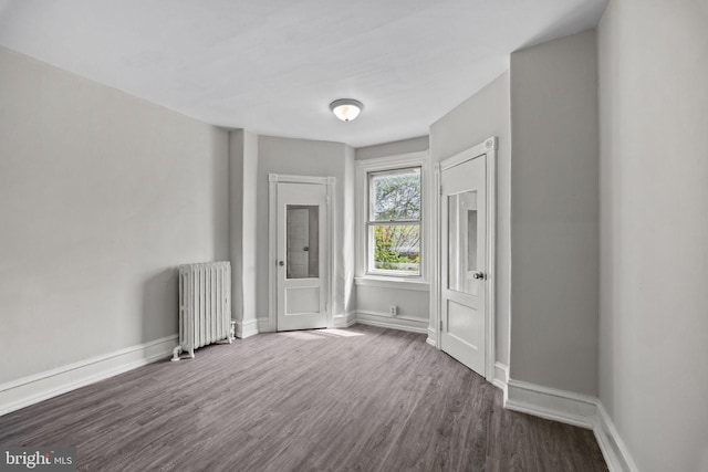 unfurnished room featuring baseboards, radiator, and dark wood-style floors