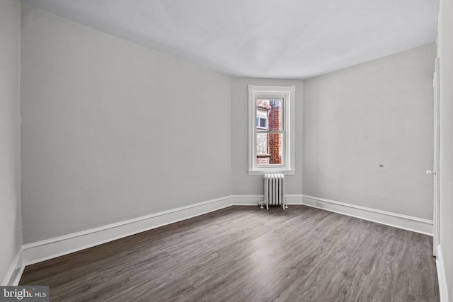 unfurnished room featuring baseboards, radiator, and dark wood-style flooring
