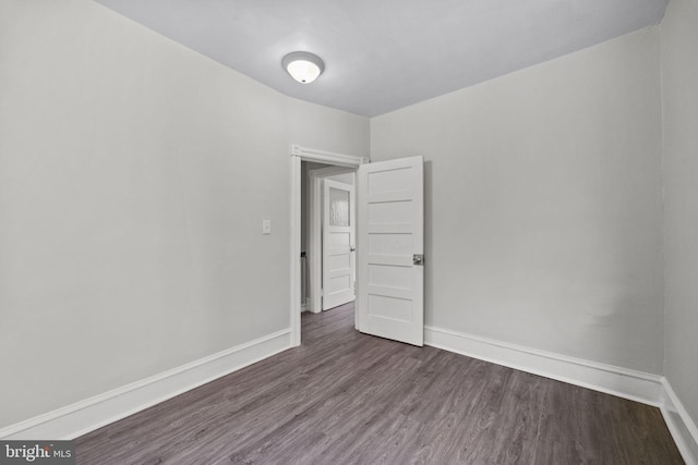 empty room featuring baseboards and dark wood finished floors