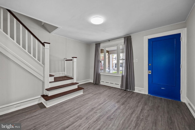 foyer entrance with baseboards, wood finished floors, stairway, and a baseboard radiator
