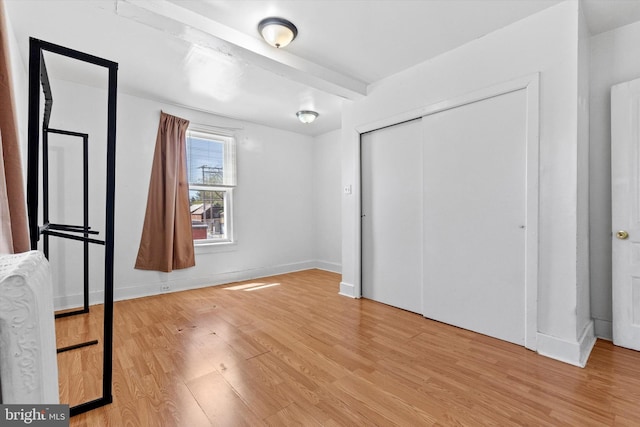 unfurnished bedroom with baseboards, light wood finished floors, and a closet
