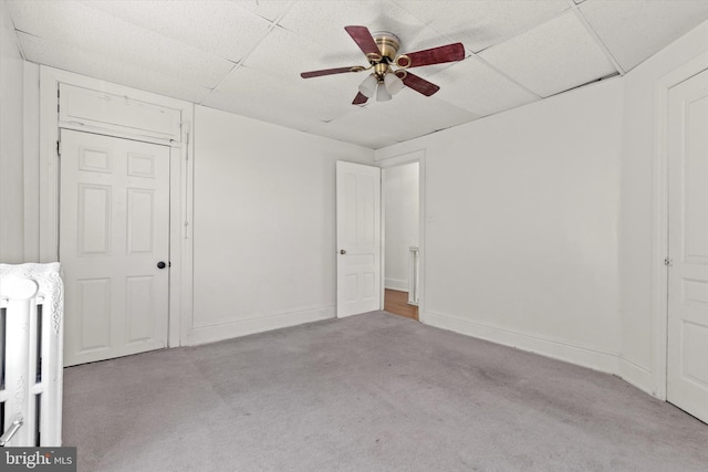 unfurnished bedroom featuring carpet floors, baseboards, a ceiling fan, and a drop ceiling